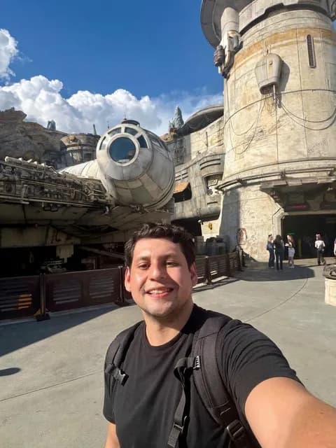 Wesley Luiz Carvalho sorrindo em frente à Millennium Falcon, em Star Wars: Galaxy's Edge